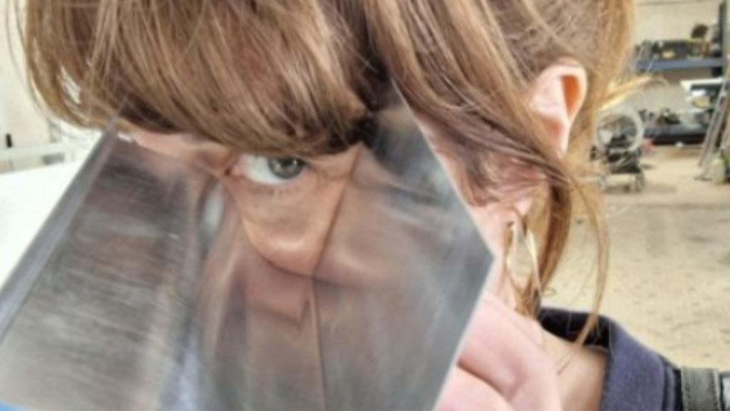 Une femme regarde à travers un morceau de métal