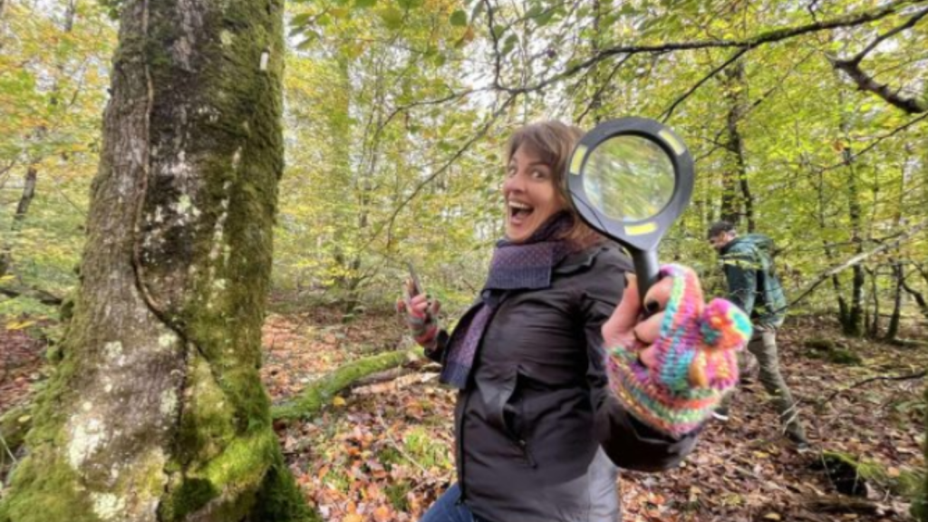 Une jeune femme souriante porte une loupe