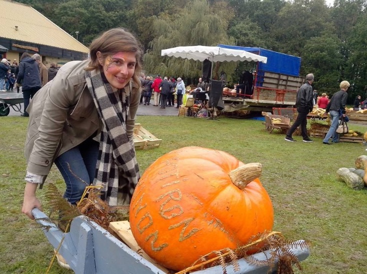 Femme poussant une brouette avec une citrouille posée dedans